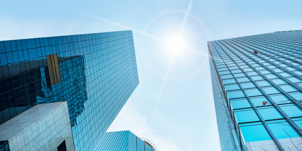 Modern glass office towers beneath a bright blue sky, representing business innovation and corporate growth.