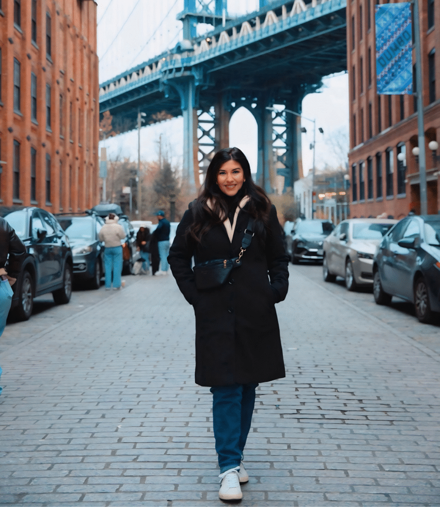 Amy walks beneath a city bridge, showcasing urban travel and exploration.