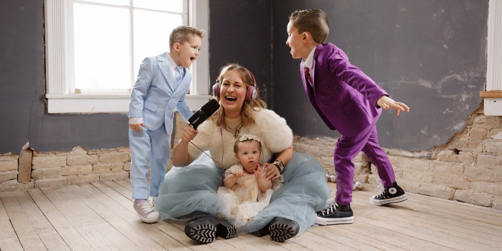 Kimberly Spencer laughs with three children holding a microphone in a playful leadership-themed photoshoot.