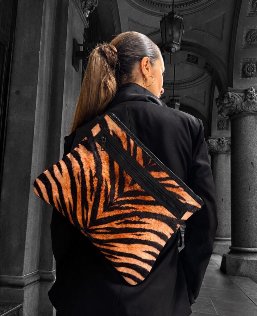 Model wearing tiger-print lvb_collection laptop bag with black blazer in architectural setting.