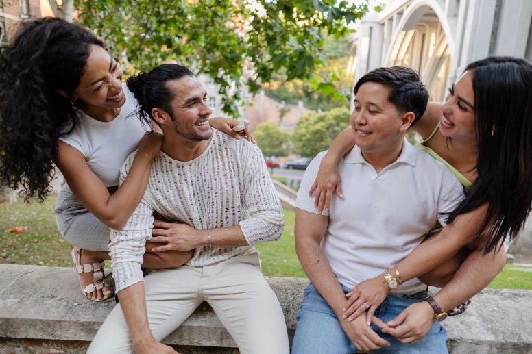 Two couples smiling together while spending time outdoors in a park.
