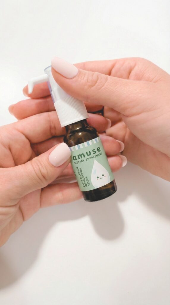 Hands holding an Amuse Drops bottle for daily early allergen introduction.