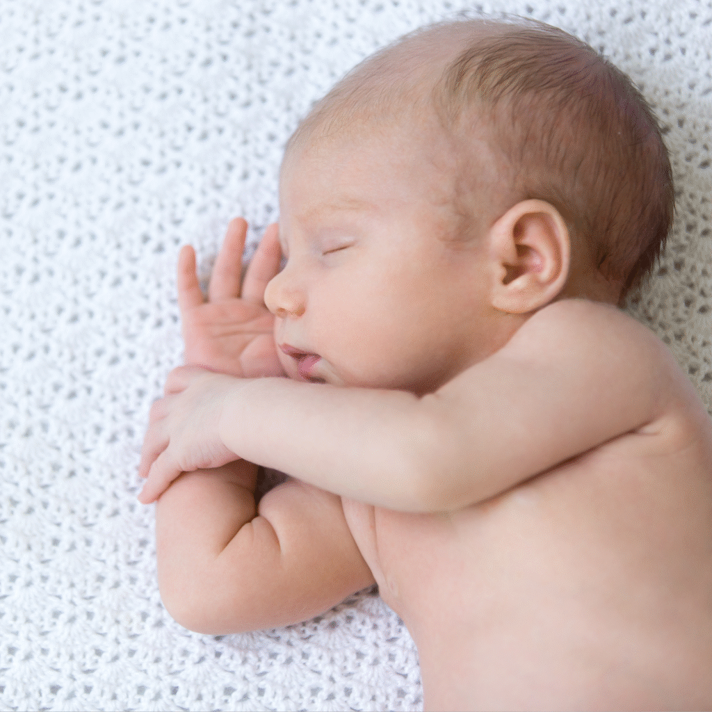 Sleeping newborn on a soft blanket, representing healthy birth and family after the fertility journey.