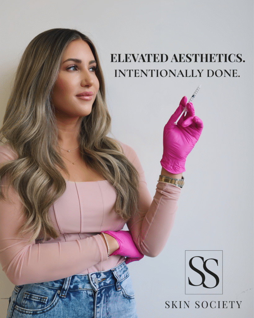 Sally Delory holding a syringe while wearing pink gloves at Skin Society Medspa & Training Center.